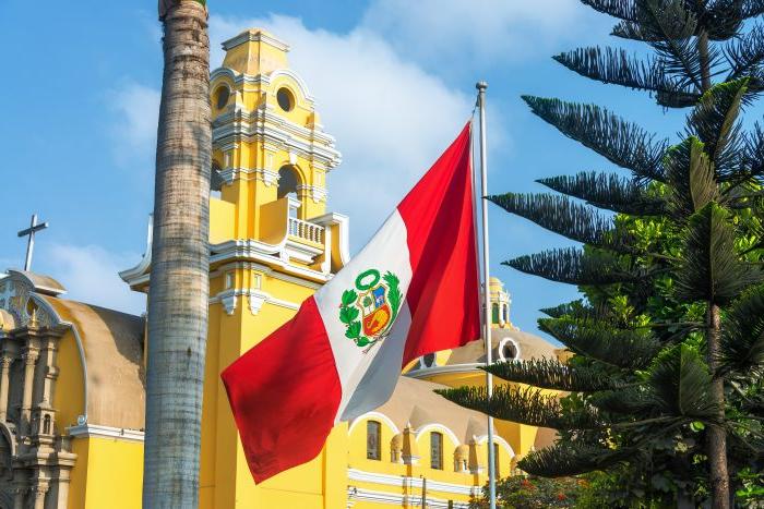 Peruvian flag flying in front of a yellow building